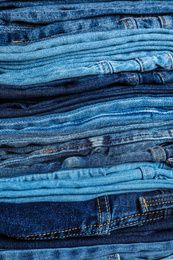 Photo of Stack of different jeans as background, closeup