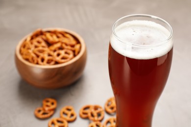 Beer and blurred bowl of pretzel crackers on background. Space for text