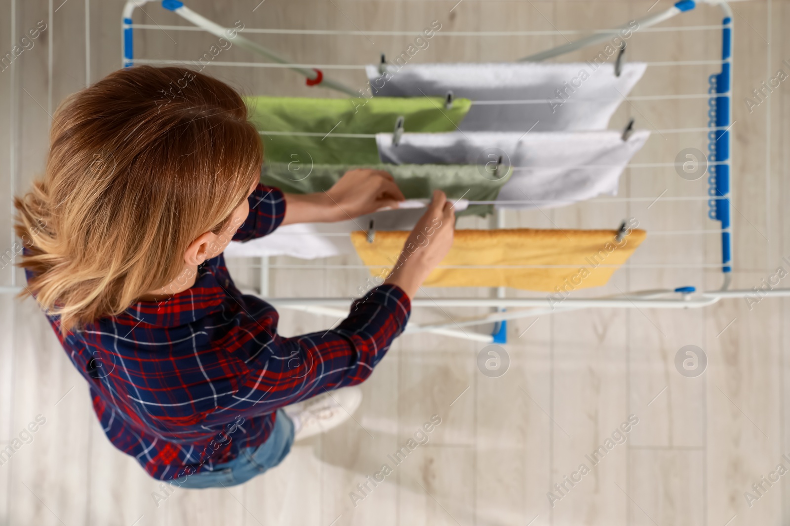 Photo of Woman hanging clean terry towels on drying rack, above view