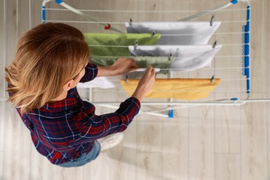 Photo of Woman hanging clean terry towels on drying rack, above view