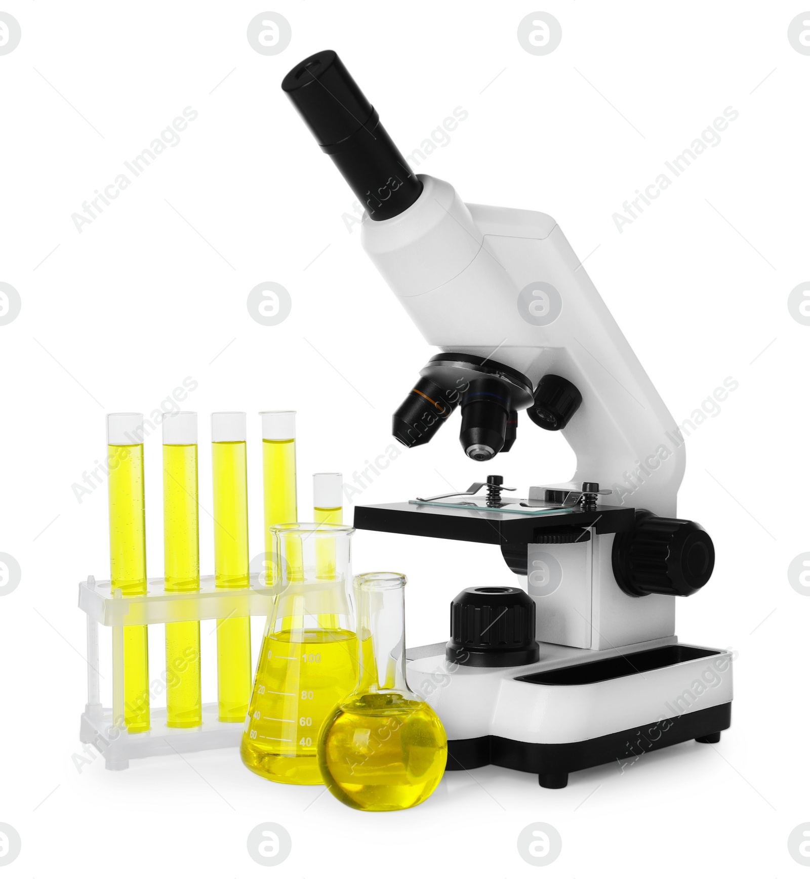 Photo of Laboratory glassware with yellow liquid and microscope isolated on white