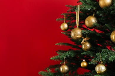 Photo of Beautifully decorated Christmas tree on red background, closeup. Space for text