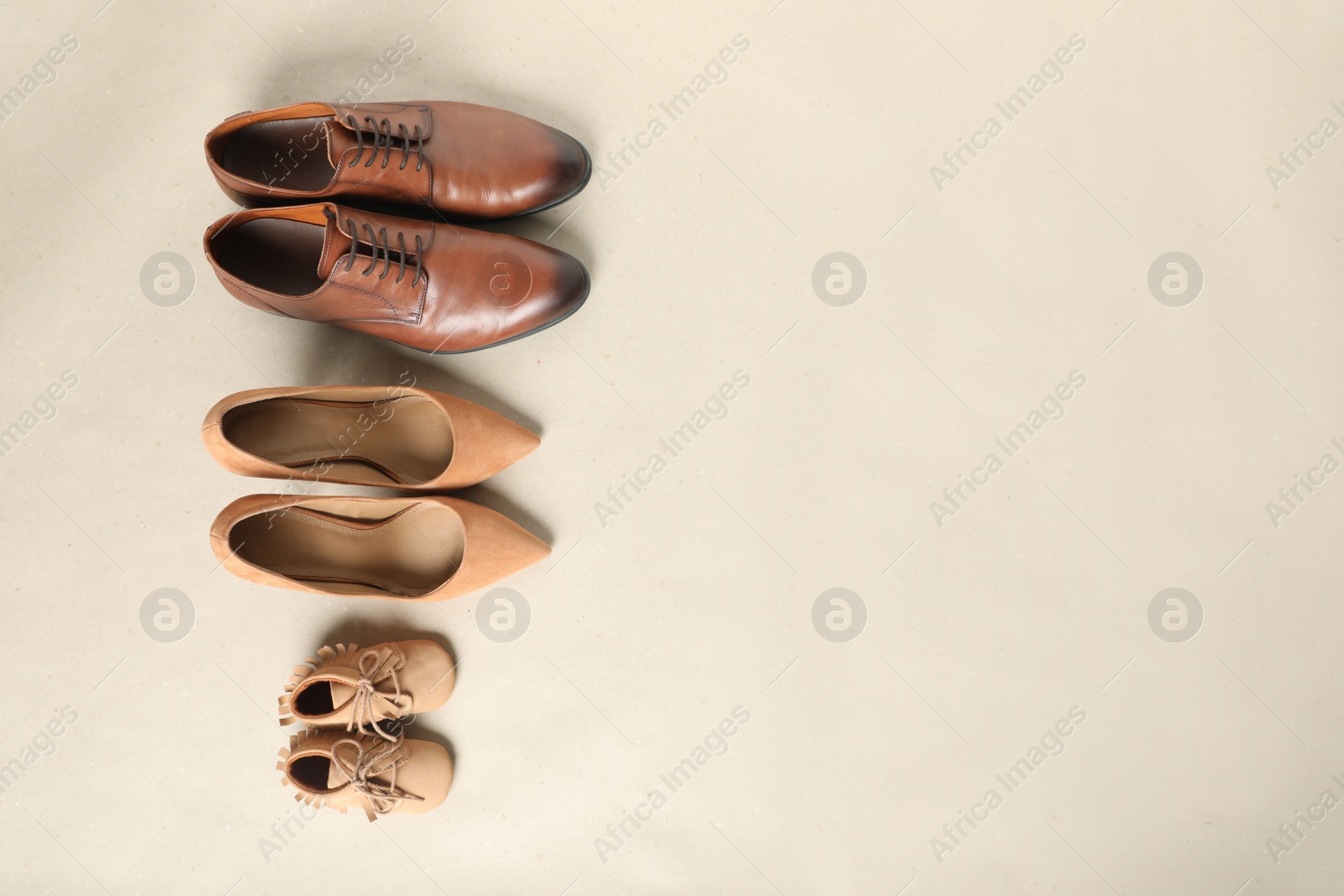 Photo of Mother's, father's and child's shoes on beige background, flat lay with space for text. Family day