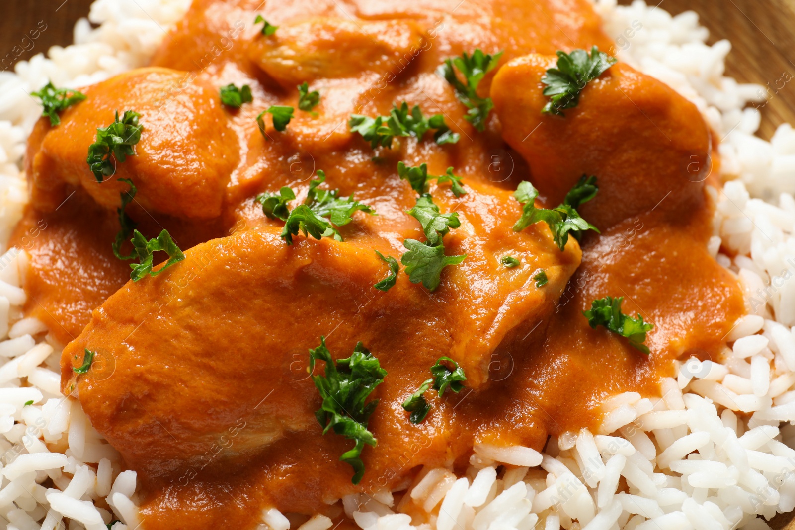 Photo of Delicious butter chicken with rice as background, closeup