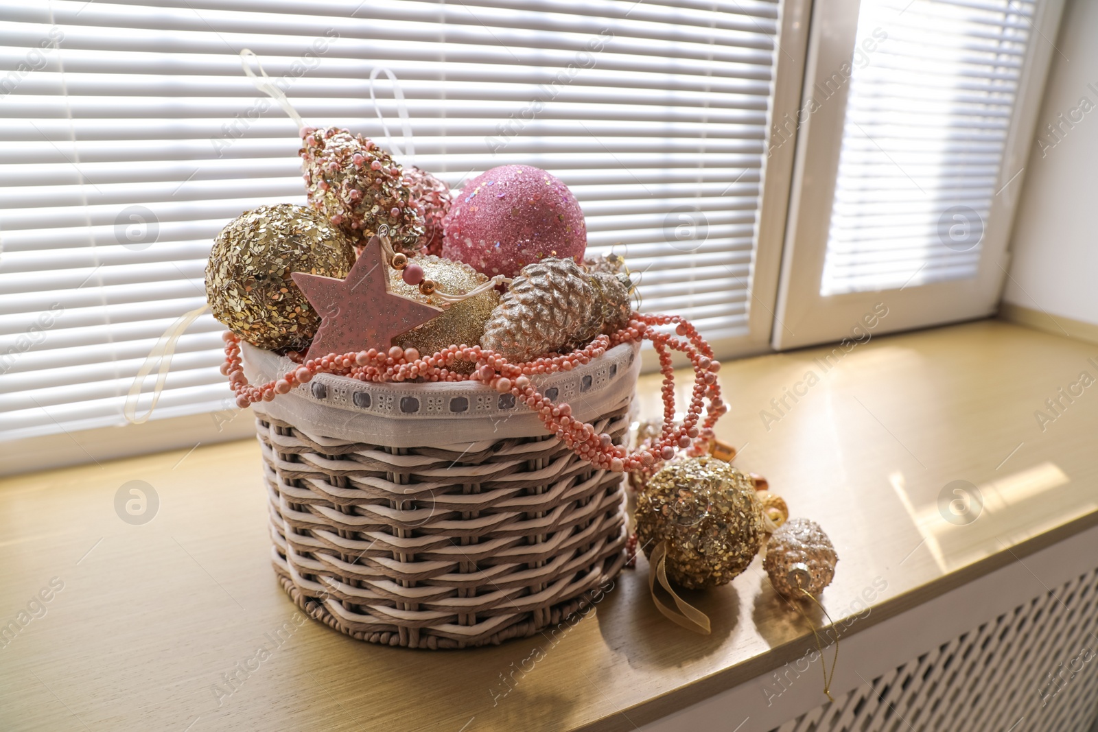 Photo of Basket with beautiful Christmas tree baubles on window sill indoors