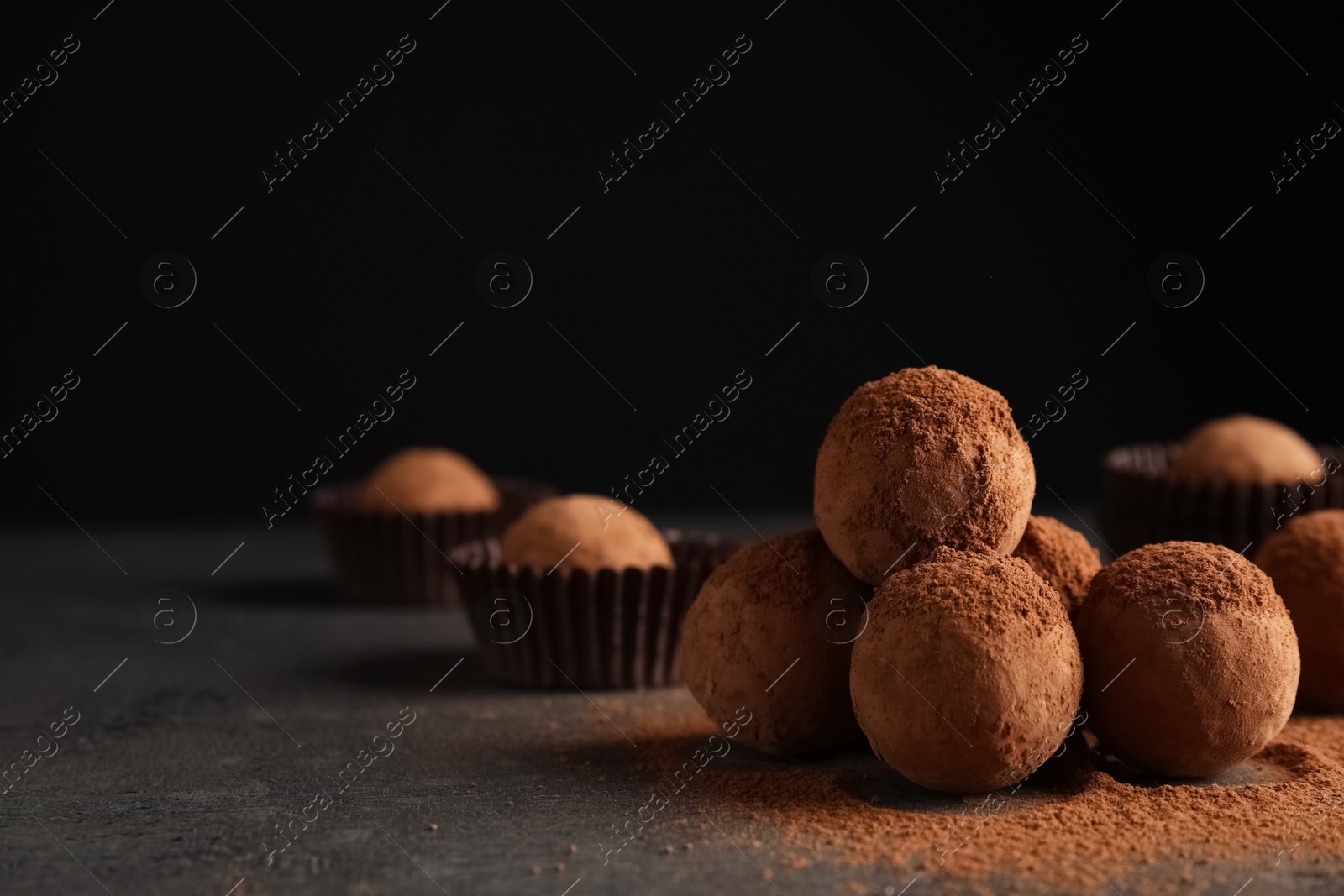 Photo of Tasty chocolate truffles powdered with cocoa on table, space for text