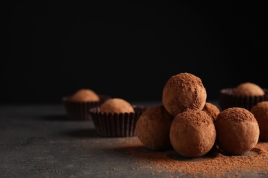 Tasty chocolate truffles powdered with cocoa on table, space for text