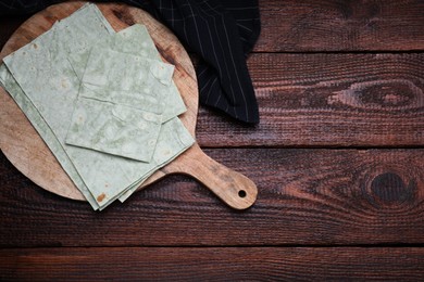 Photo of Delicious green folded Armenian lavash on wooden table, flat lay. Space for text