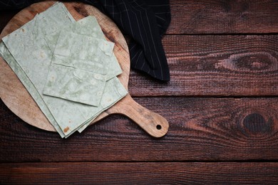 Delicious green folded Armenian lavash on wooden table, flat lay. Space for text