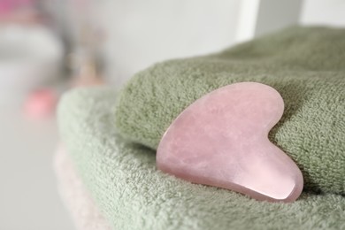 Rose quartz gua sha tool on soft towel, closeup