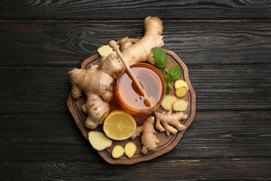 Photo of Ginger and other natural cold remedies on black wooden table, top view