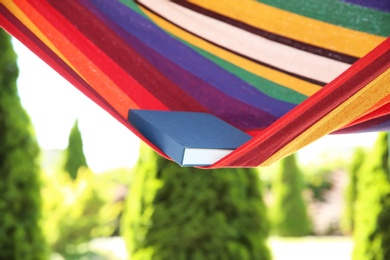 Photo of Colorful hammock with book outdoors on sunny day