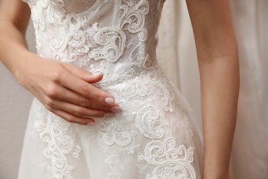Photo of Woman trying on beautiful wedding dress indoors, closeup