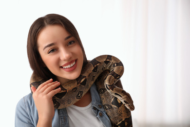 Young woman with her boa constrictor at home. Exotic pet