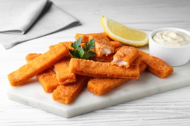 Photo of Tasty fish fingers served on white wooden table