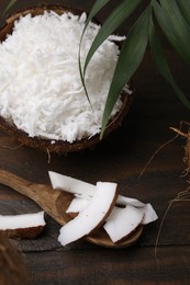 Coconut flakes, spoon, nut and palm leaf on wooden table