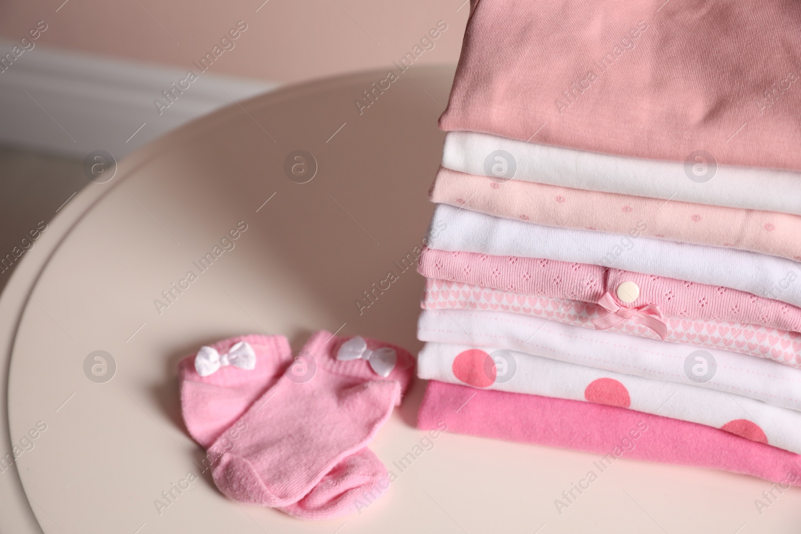 Photo of Stack of clean girl's clothes and socks on table