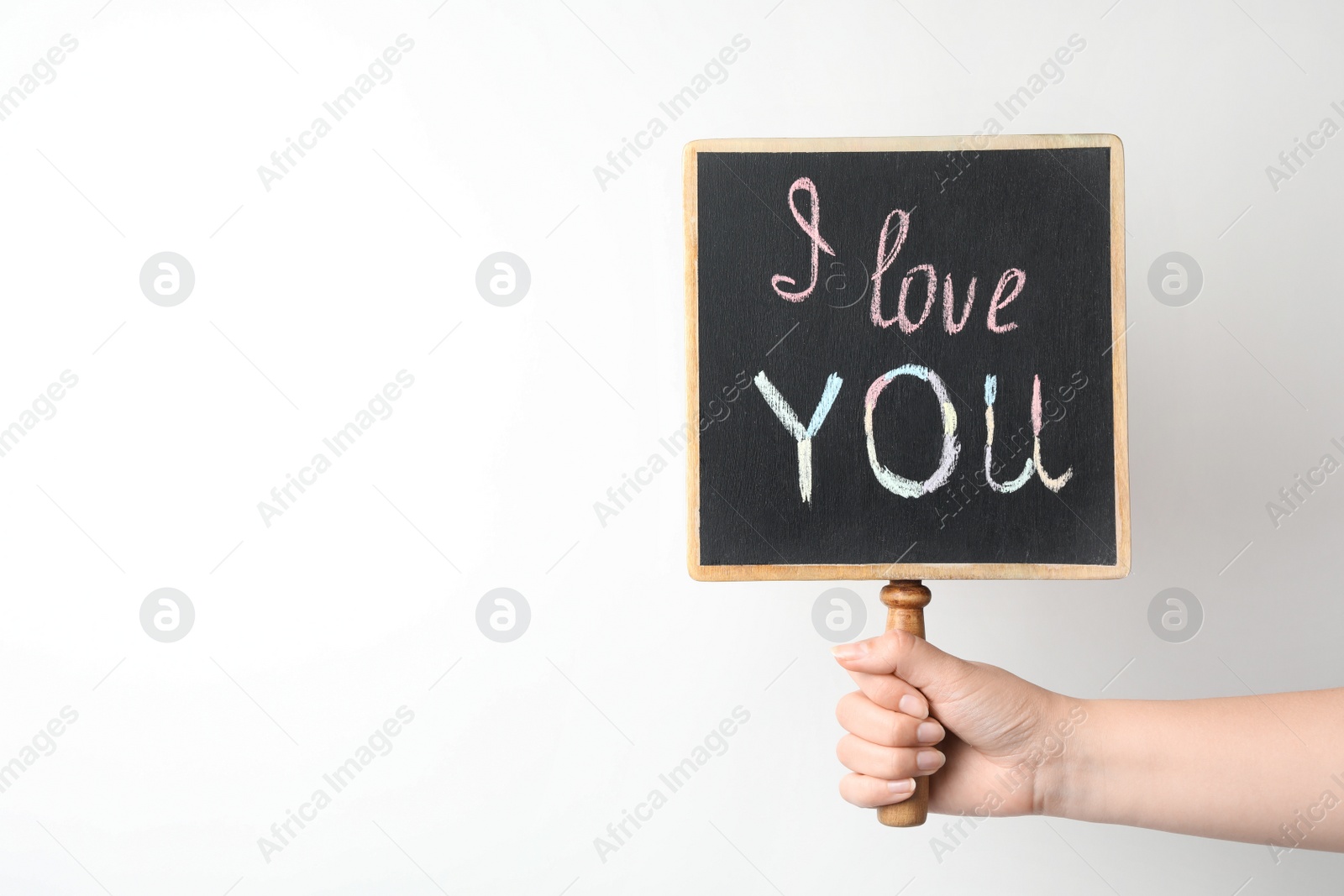 Photo of Young woman holding chalkboard with words I LOVE YOU on white background. Space for text