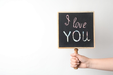 Photo of Young woman holding chalkboard with words I LOVE YOU on white background. Space for text