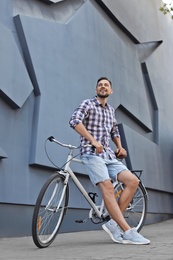 Photo of Man with bicycle on street near gray wall