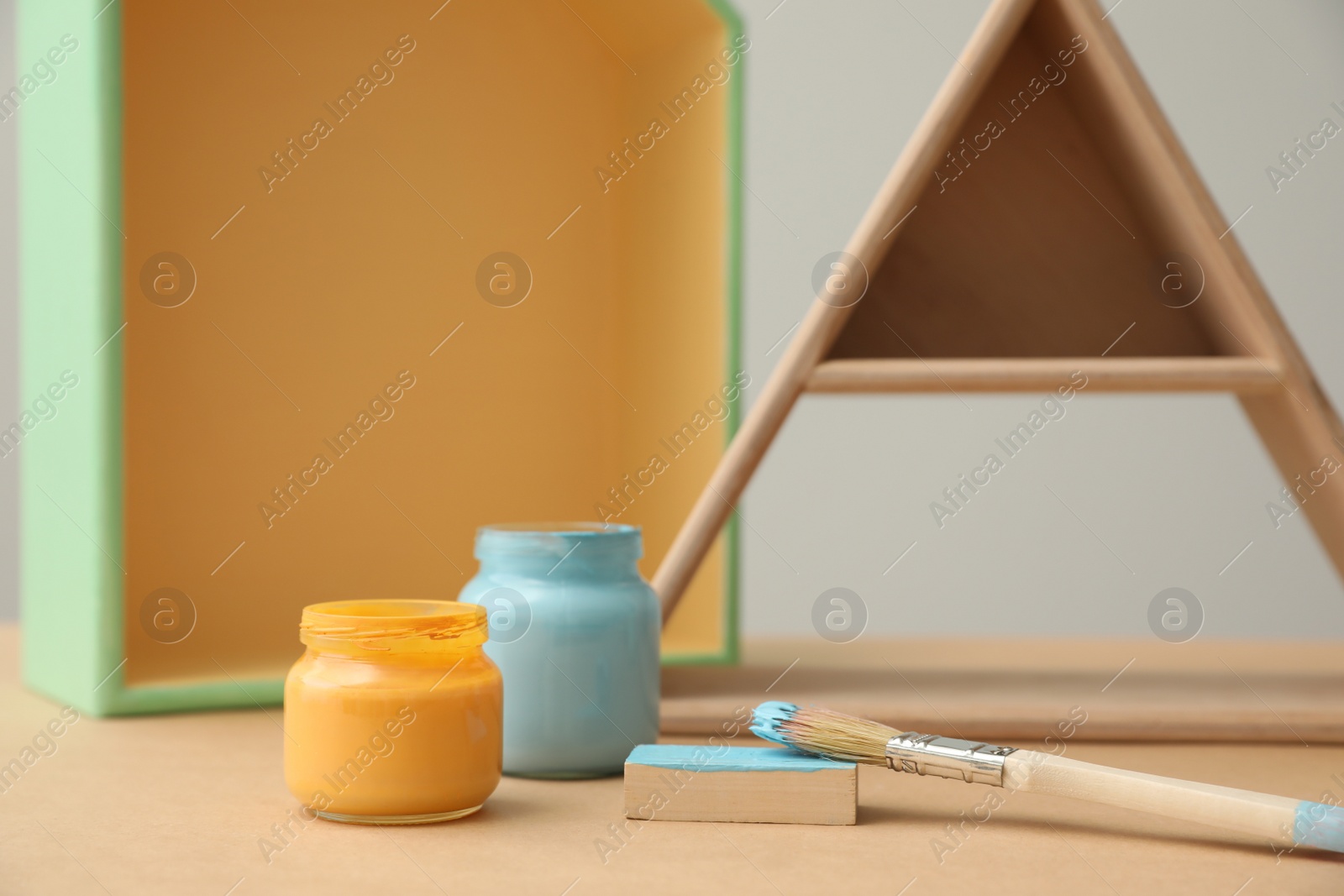 Photo of Jars of paints and brush on wooden table, closeup. Interior element