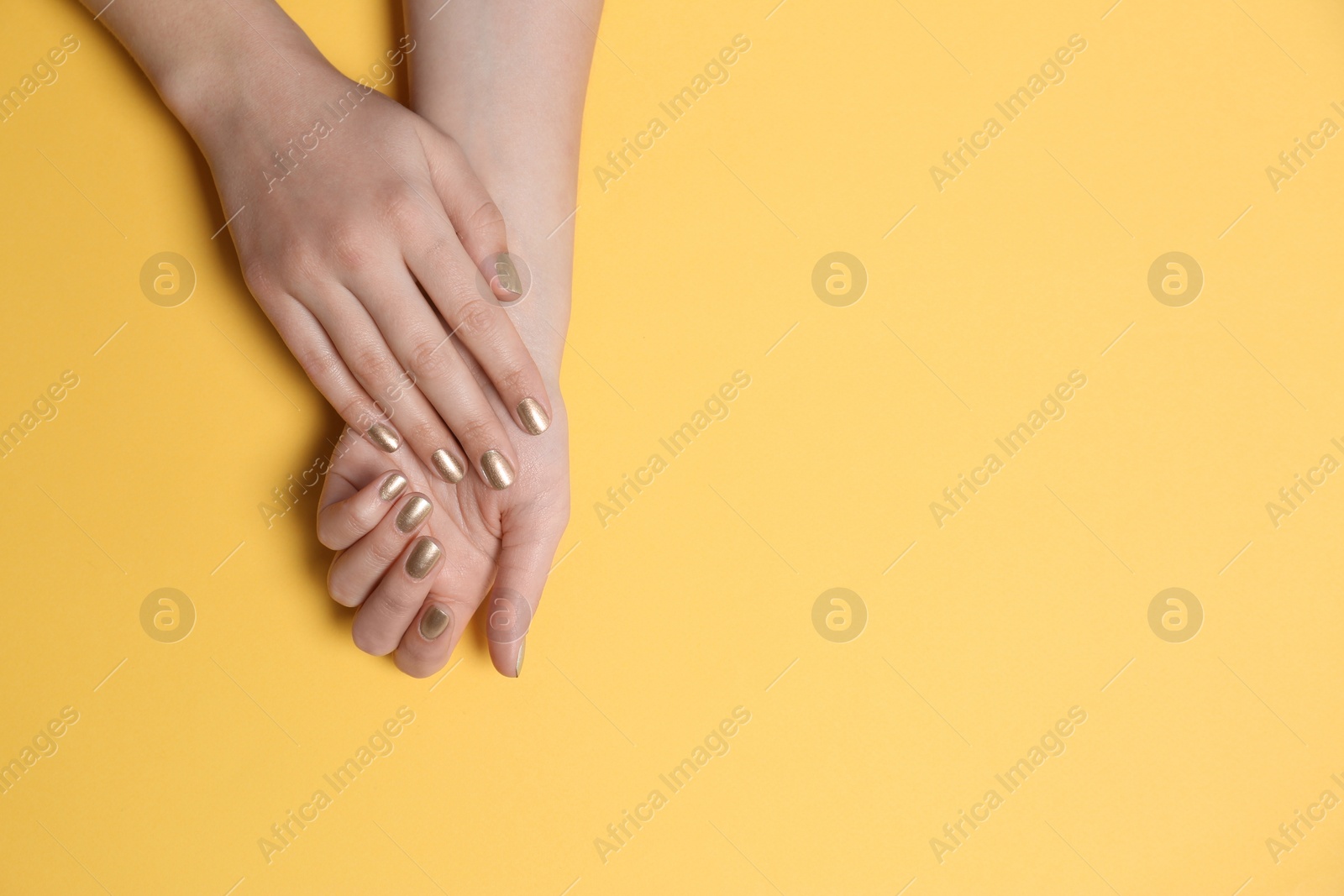 Photo of Woman showing golden manicure on color background, top view with space for text. Nail polish trends