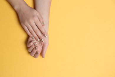 Photo of Woman showing golden manicure on color background, top view with space for text. Nail polish trends