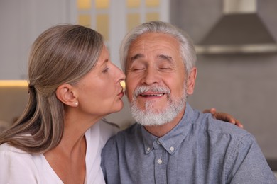 Photo of Senior woman kissing her beloved man in kitchen