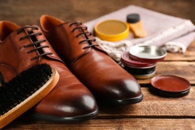 Photo of Shoe care products and footwear on wooden table, closeup