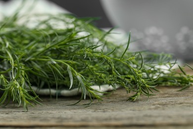 Photo of Bunch of fresh tarragon sprigs on wooden table, closeup