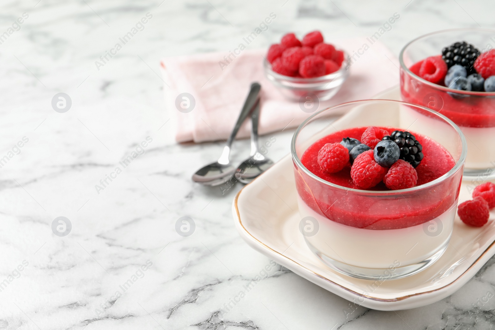 Photo of Delicious panna cotta with fruit coulis and fresh berries served on white marble table. Space for text