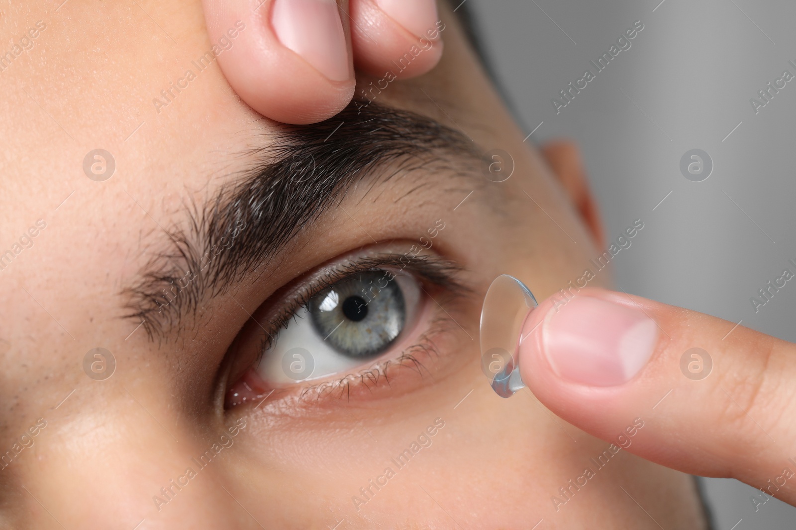 Photo of Closeup view of young man putting in contact lens