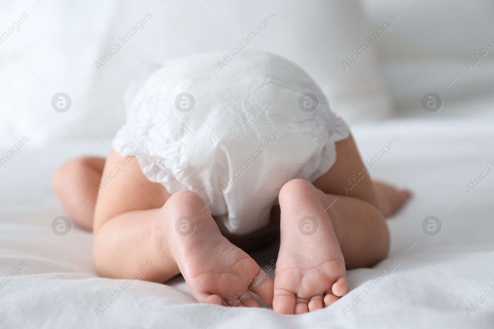 Photo of Cute little baby in diaper on bed