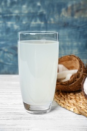 Photo of Glass of coconut water and fresh nuts on wooden table