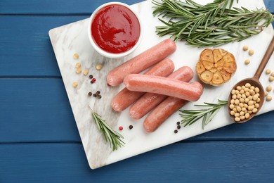 Photo of Delicious vegetarian sausages with rosemary, soybeans and garlic on blue wooden table, top view
