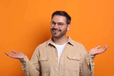 Photo of Portrait of smiling man in stylish glasses on orange background
