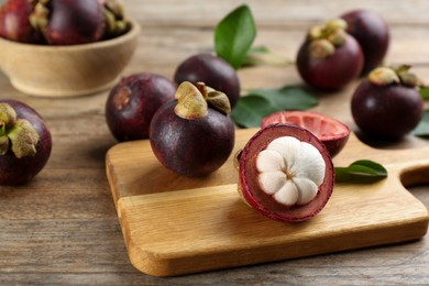 Photo of Delicious tropical mangosteen fruits on wooden table