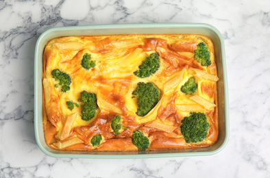 Photo of Tasty broccoli casserole in baking dish on white marble table, top view