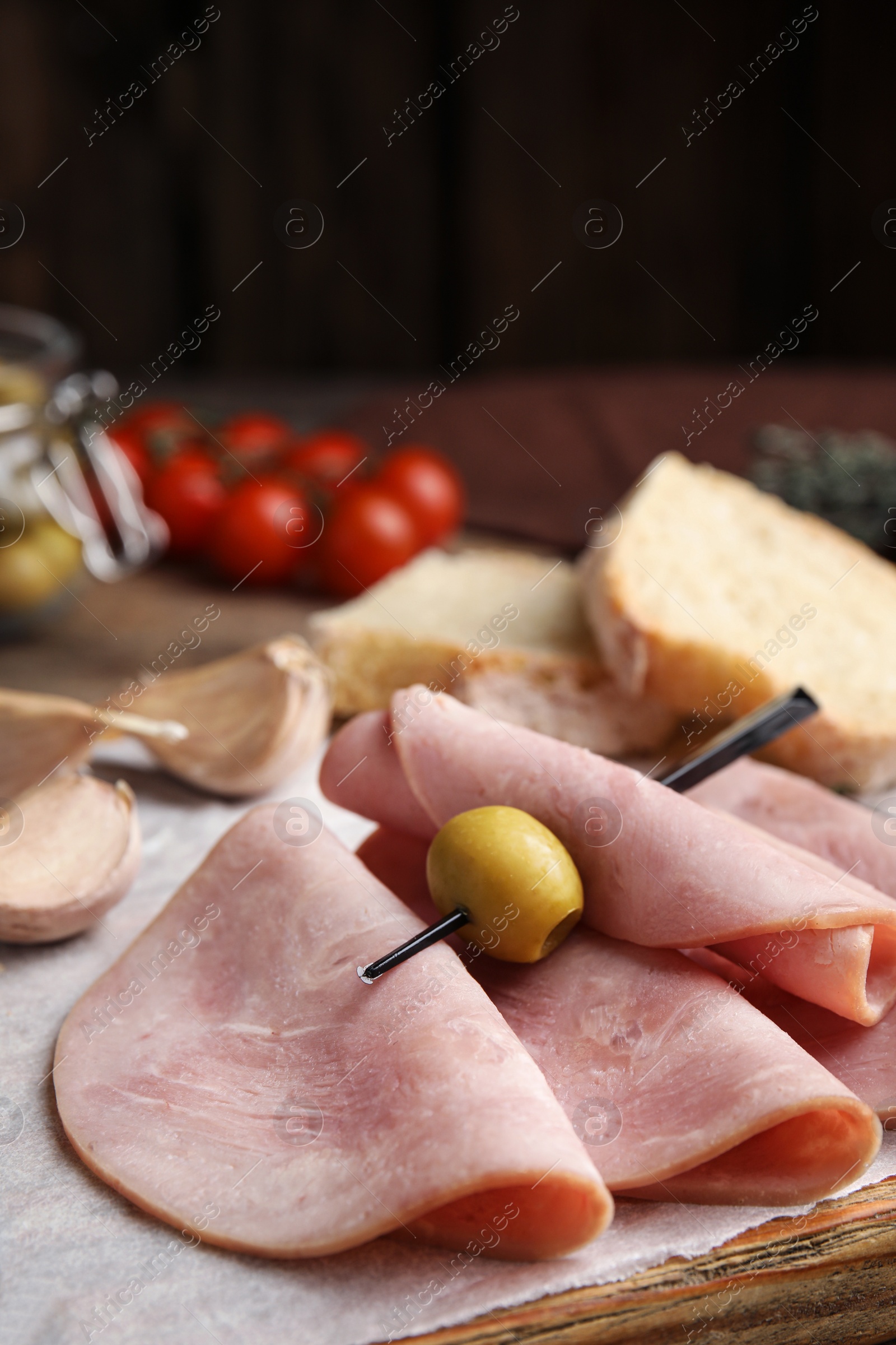 Photo of Slices of tasty ham with olive on table, closeup