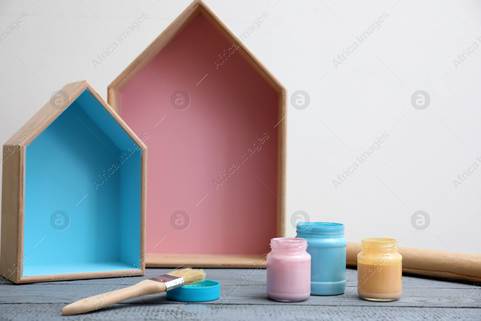 Photo of Brush with paint and wooden houses on grey table