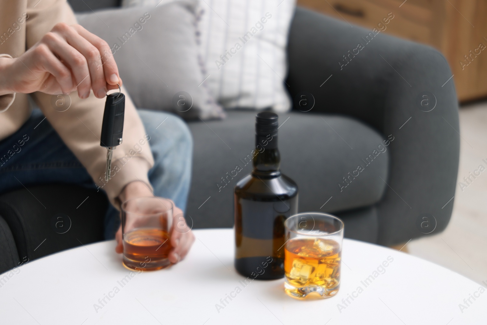 Photo of Man with glass of alcoholic drink and car keys at table, closeup. Don't drink and drive concept