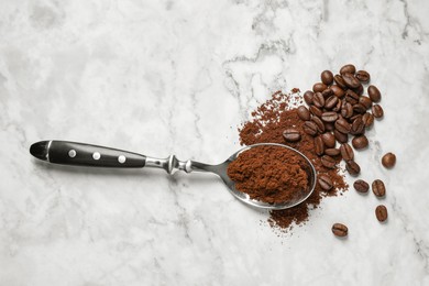 Photo of Ground coffee and roasted beans on white marble table, top view