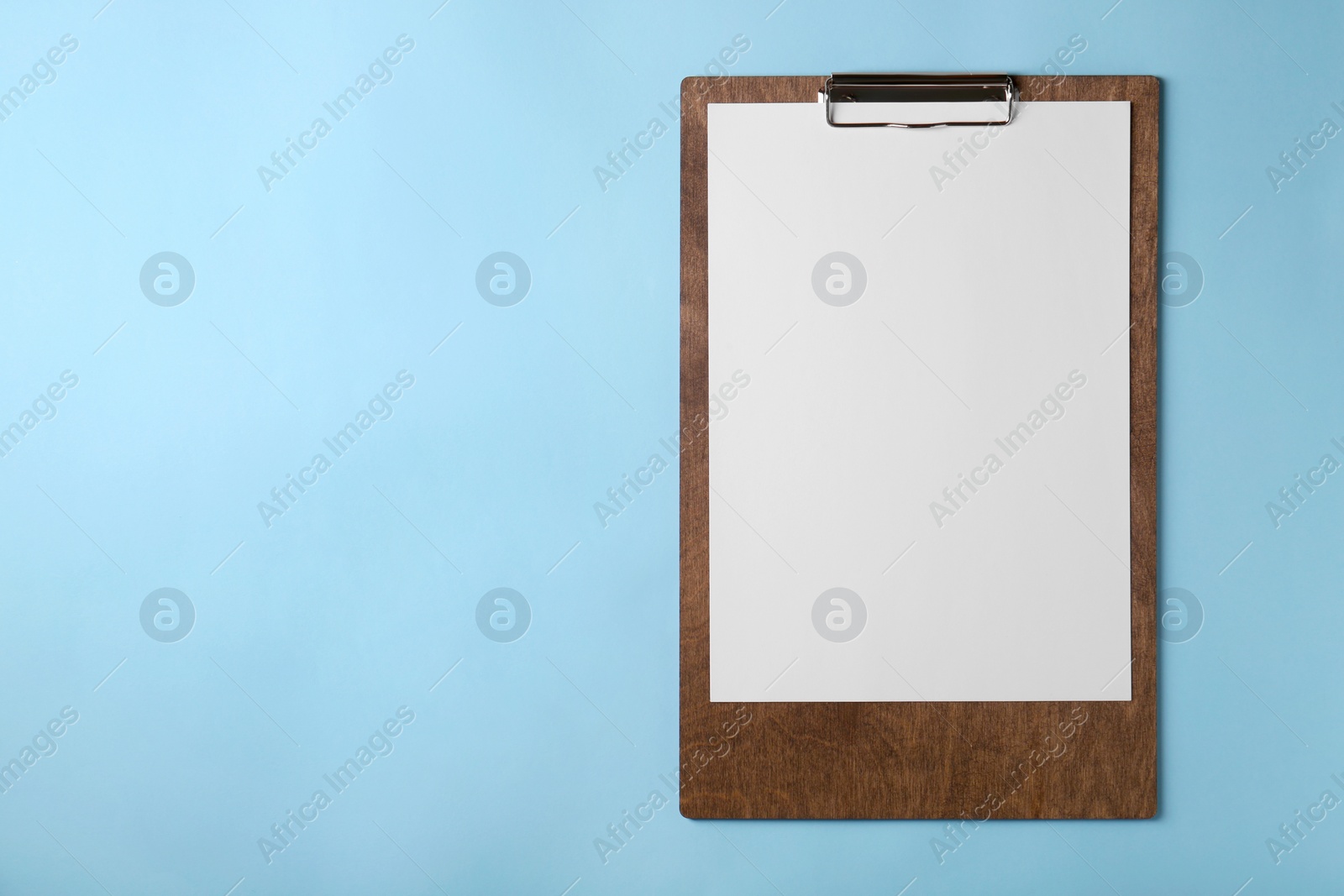 Photo of New wooden clipboard with sheet of blank paper on light blue background, top view. Space for text