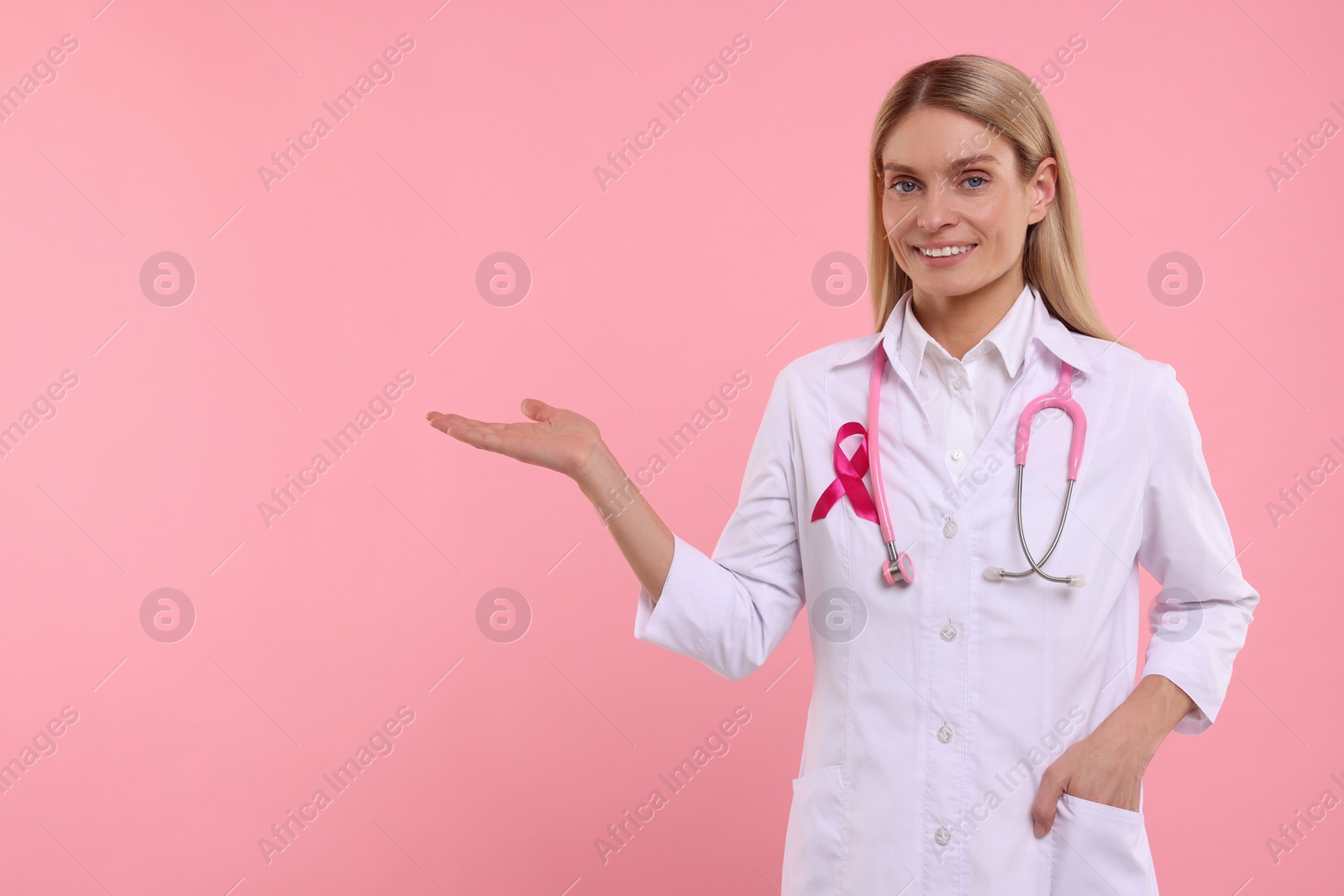 Photo of Doctor with pink ribbon and stethoscope on color background, space for text. Breast cancer awareness