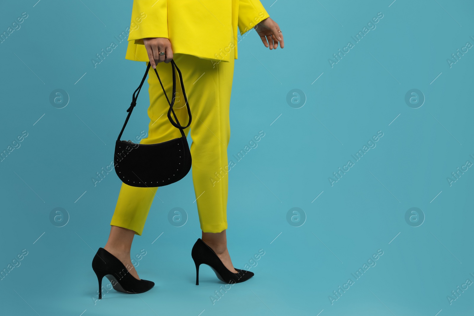 Photo of Fashionable woman with stylish bag on light blue background, closeup. Space for text