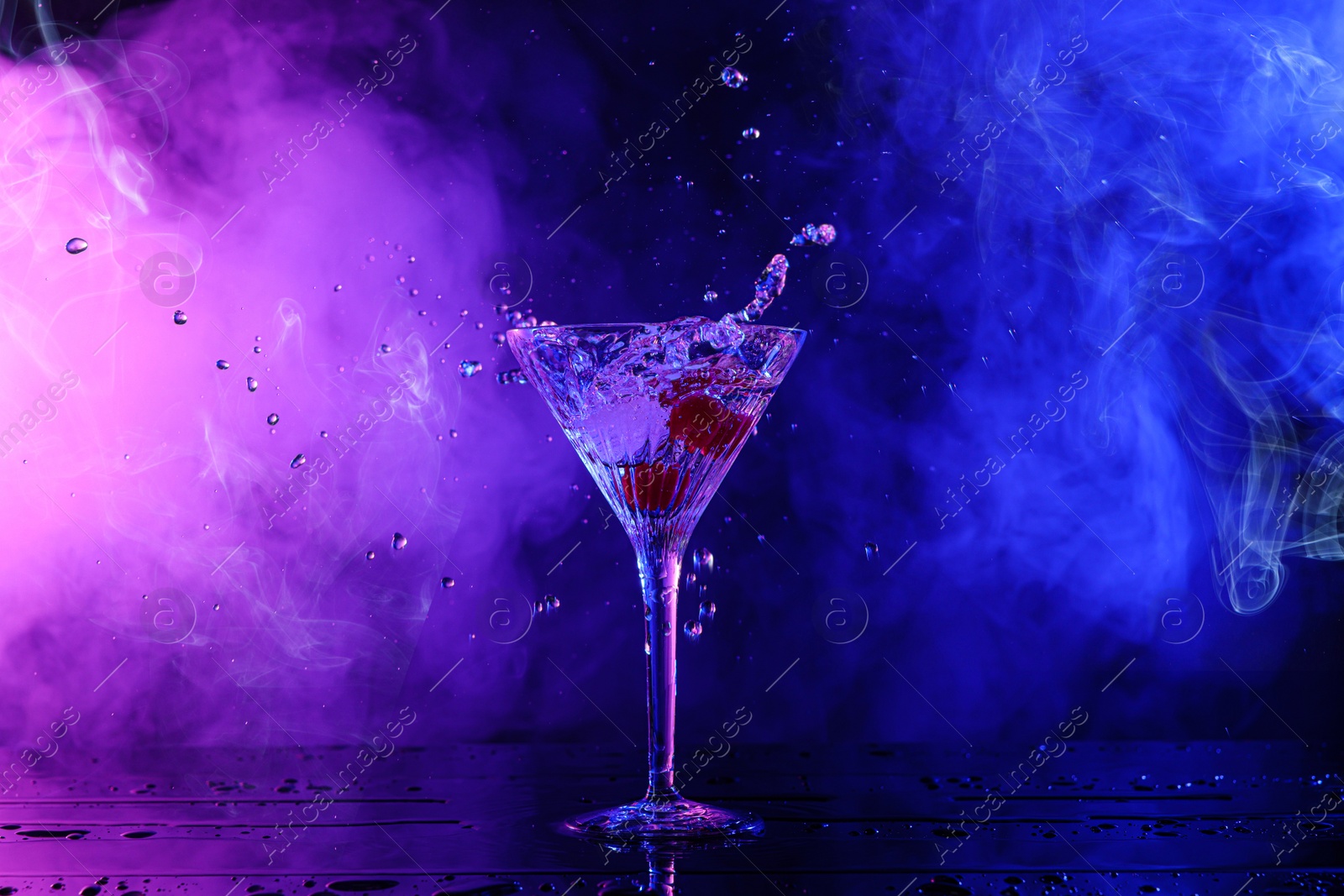 Photo of Martini splashing out of glass on table in neon lights