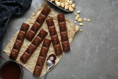 Photo of Tasty chocolate bars and nuts on grey table, flat lay. Space for text