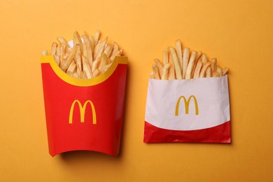 Photo of MYKOLAIV, UKRAINE - AUGUST 12, 2021: Small and big portions of McDonald's French fries on orange background, flat lay