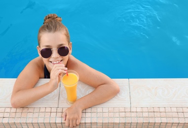 Happy little girl with drink in swimming pool