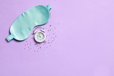 Photo of Sleeping mask, alarm clock and confetti on violet background, flat lay. Space for text